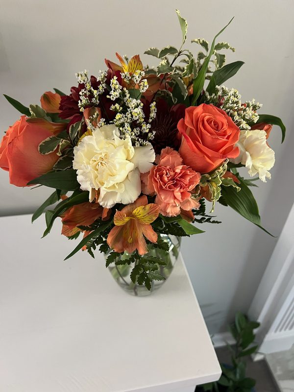 Orange roses, cream carnations and alstroemeria in a vase