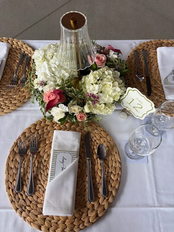 White hydrangea centerpiece with pink roses on a woven charger
