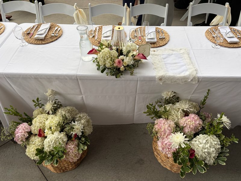 Head table with hydrangea baskets at an outdoor wedding