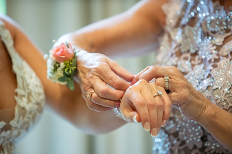 Corsage being fastened on the mother of the bride