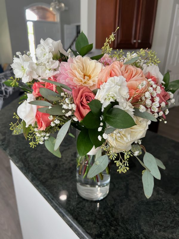 Peach and white arrangement with eucalyptus on a dark counter