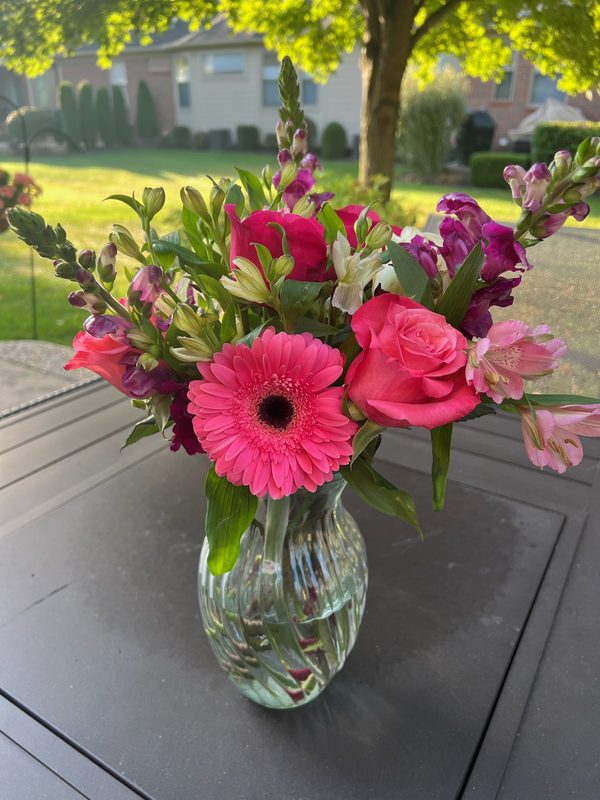 Bright pink gerbera, roses and snapdragons in a glass vase