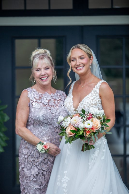 Bride with her mother, holding a peach bouquet