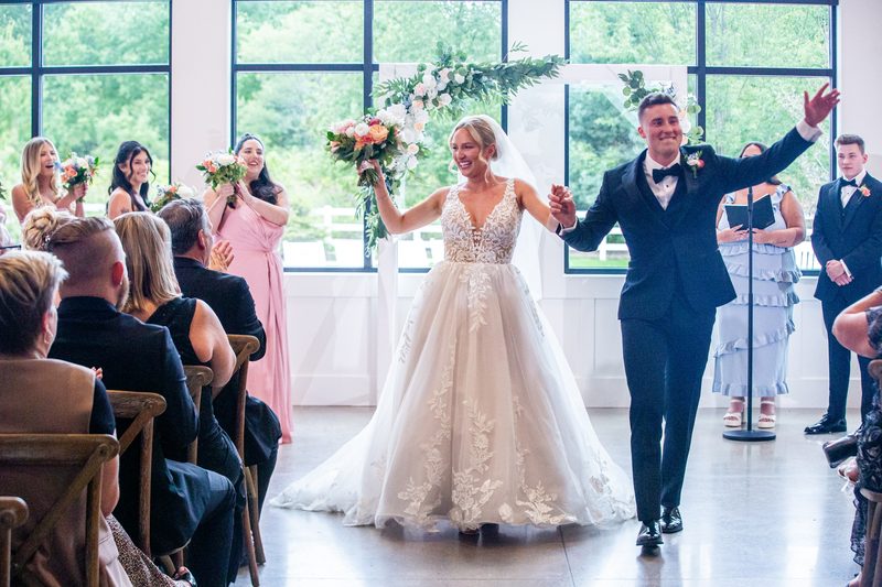 Newlyweds walking down the aisle, bouquet raised