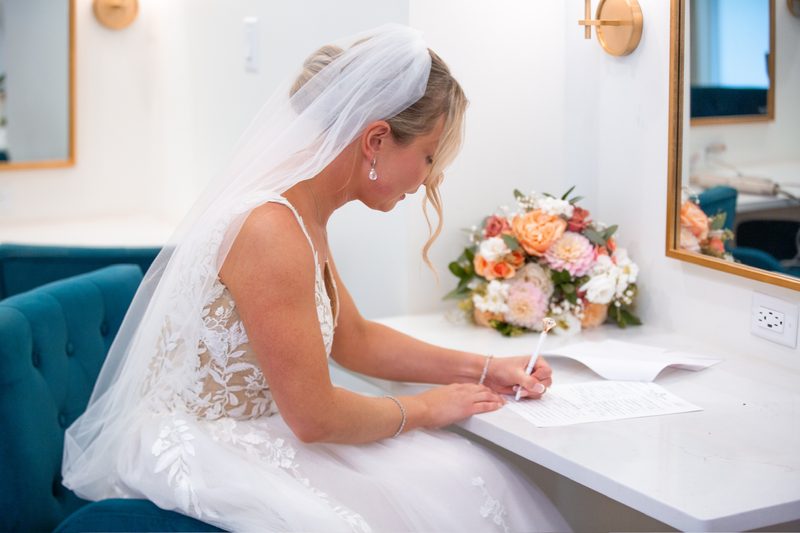 Bride signing the marriage license beside her bouquet