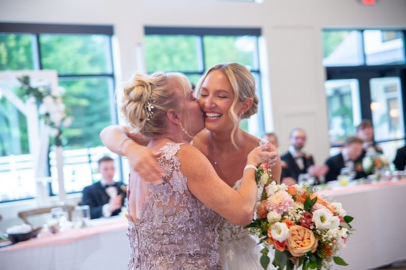 Bride hugging a guest at the reception, bouquet in hand