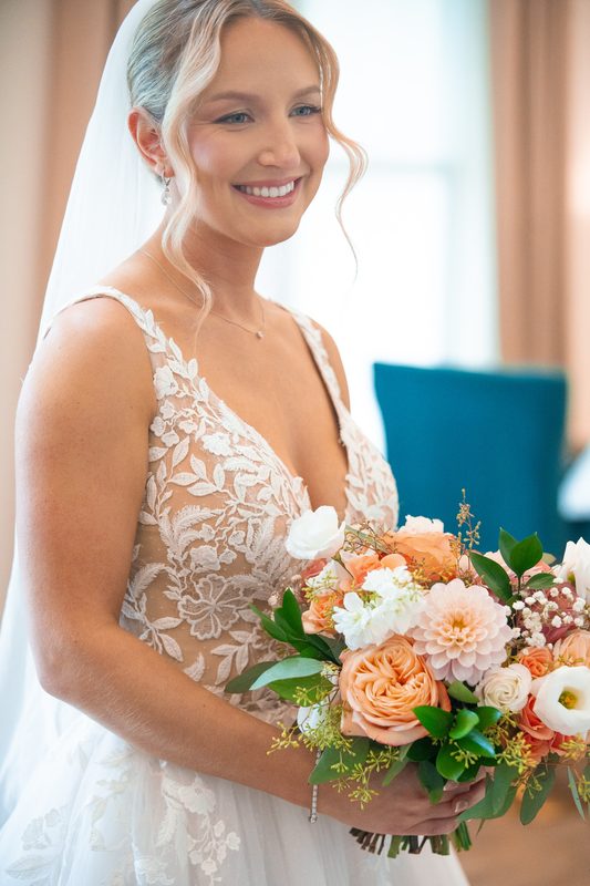 Smiling bride with a peach and white bouquet