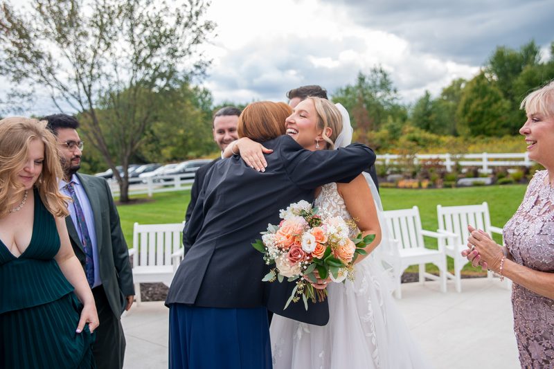 Wedding guests embracing the bride outdoors