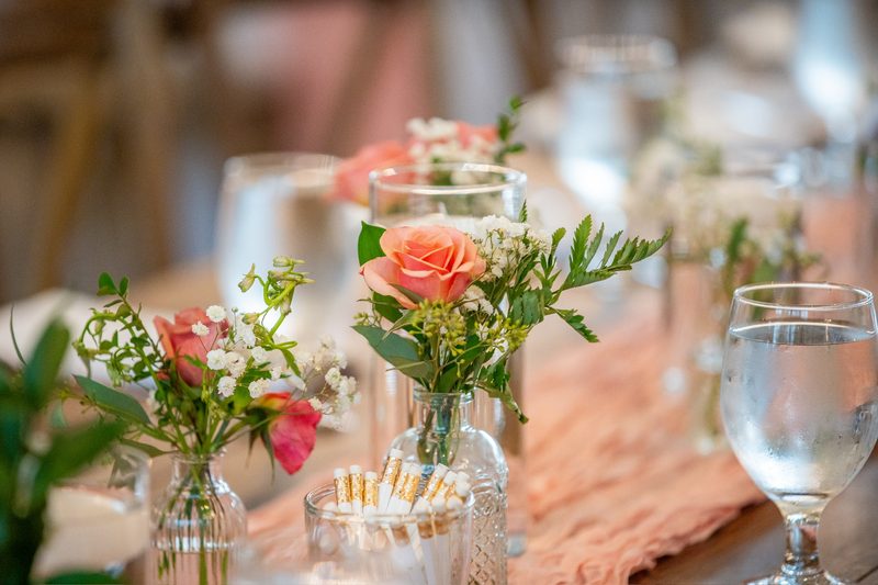 Bud vases with pink roses along a reception table
