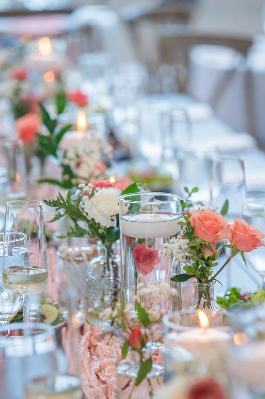 Floating candles and bud vases along a reception table
