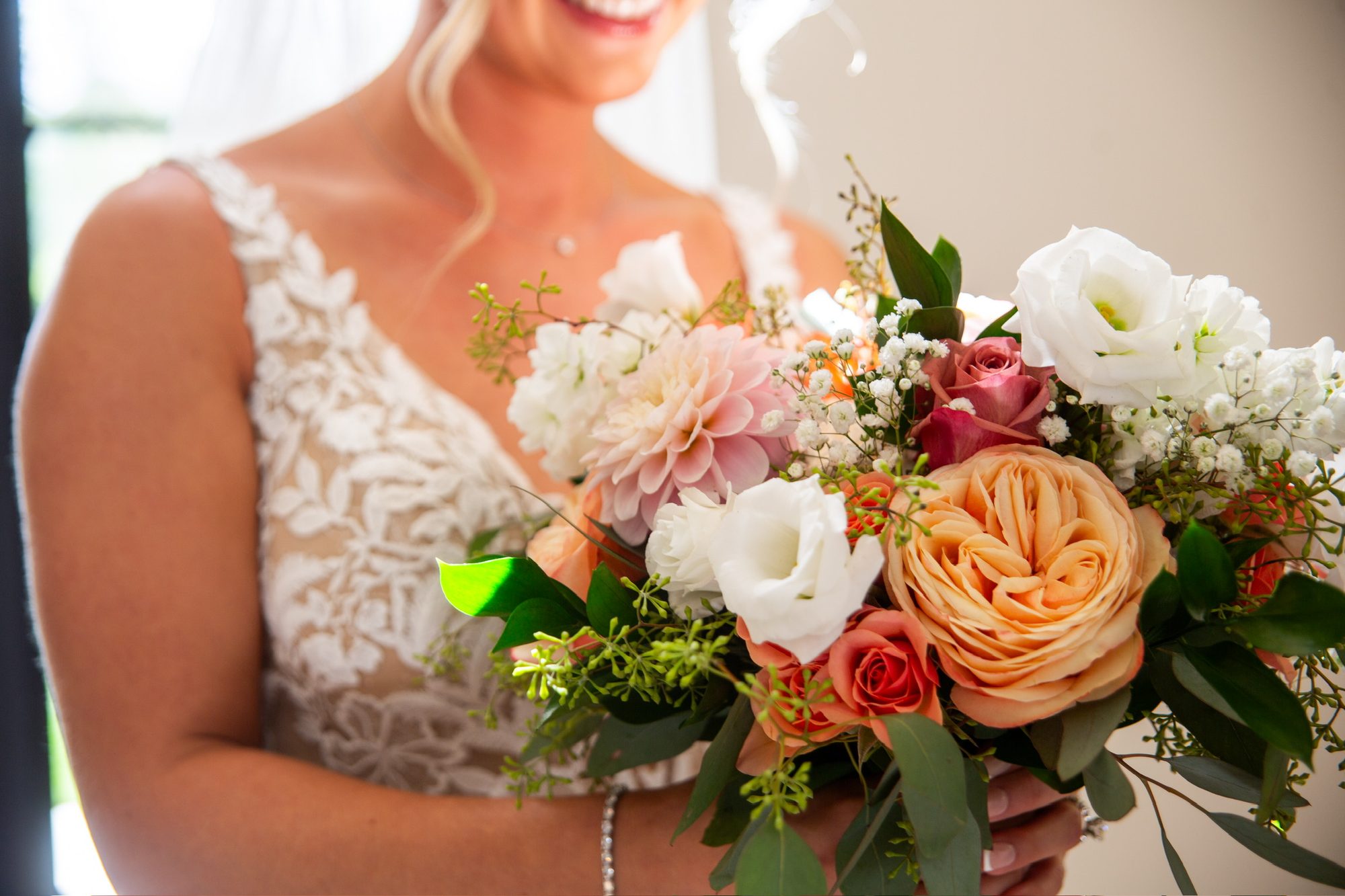 Bride holding a peach, white and coral bouquet by Kim's Florals